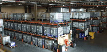 A wide shot overlooking a warehouse full of organised chemical IBC containers on shelves.