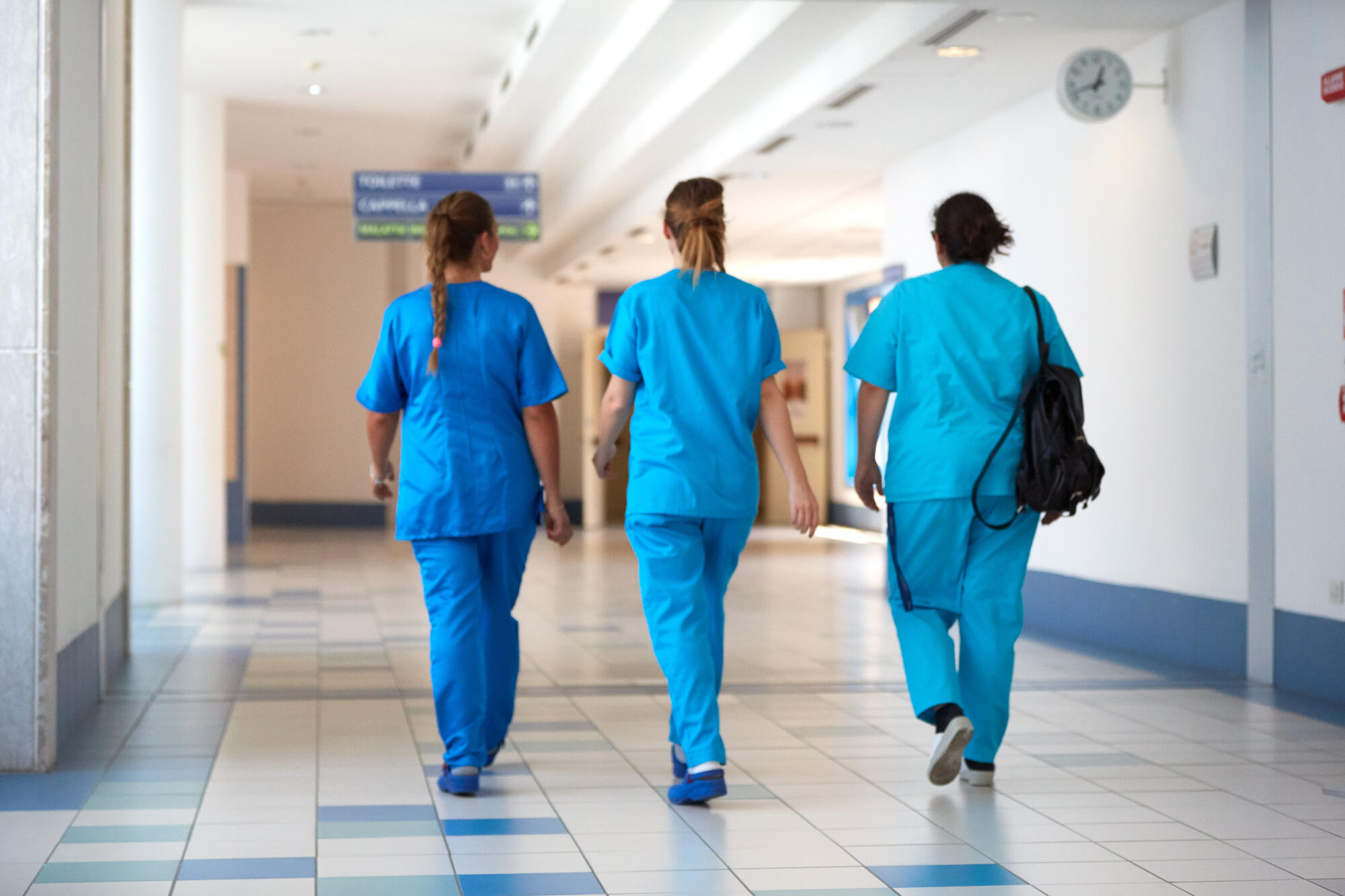 Hopsital employees walking down a quiet white hospital corridor