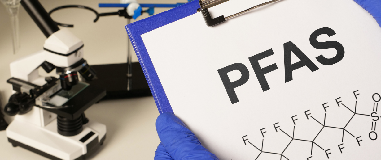 Clipboard in the foreground that says PFAS with a visual chemical composition underneath
