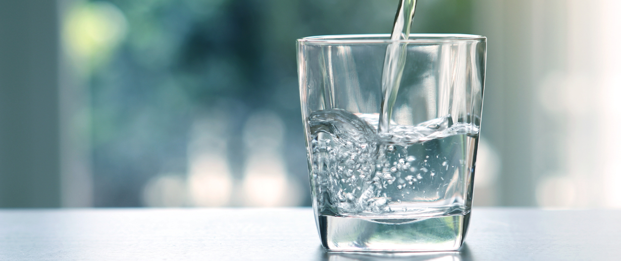 Close up the pouring purified fresh drink water from the bottle on table in living room