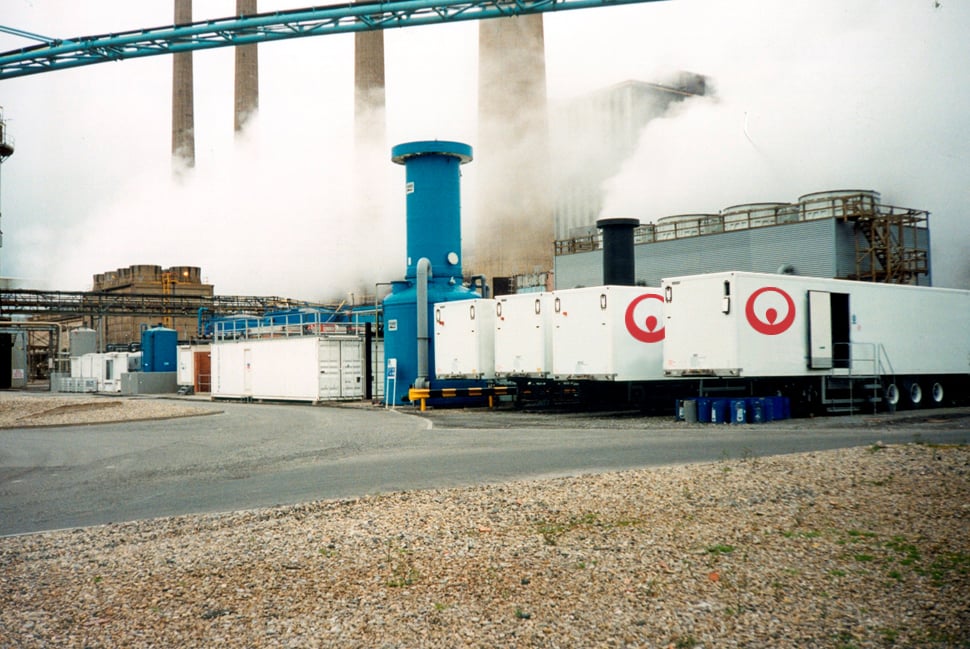Several Veolia mobile water treatment trailers, identified by their white exterior and red circular company logos, are stationed at an industrial facility.