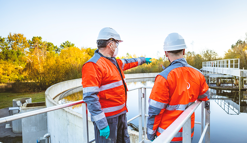 Two Veolia Water Treatment Engineers stand looking over a water treatment site.