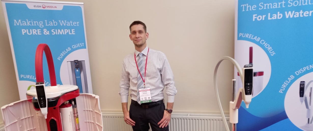 Etienne standing in the middle of an event stand with banners left and right