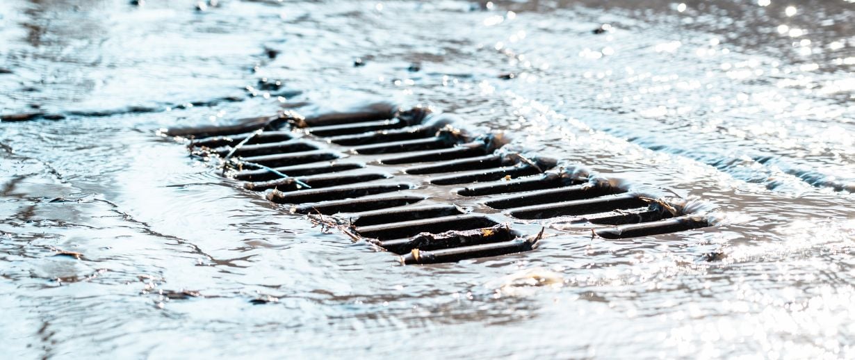 A drain overflowing with running water.