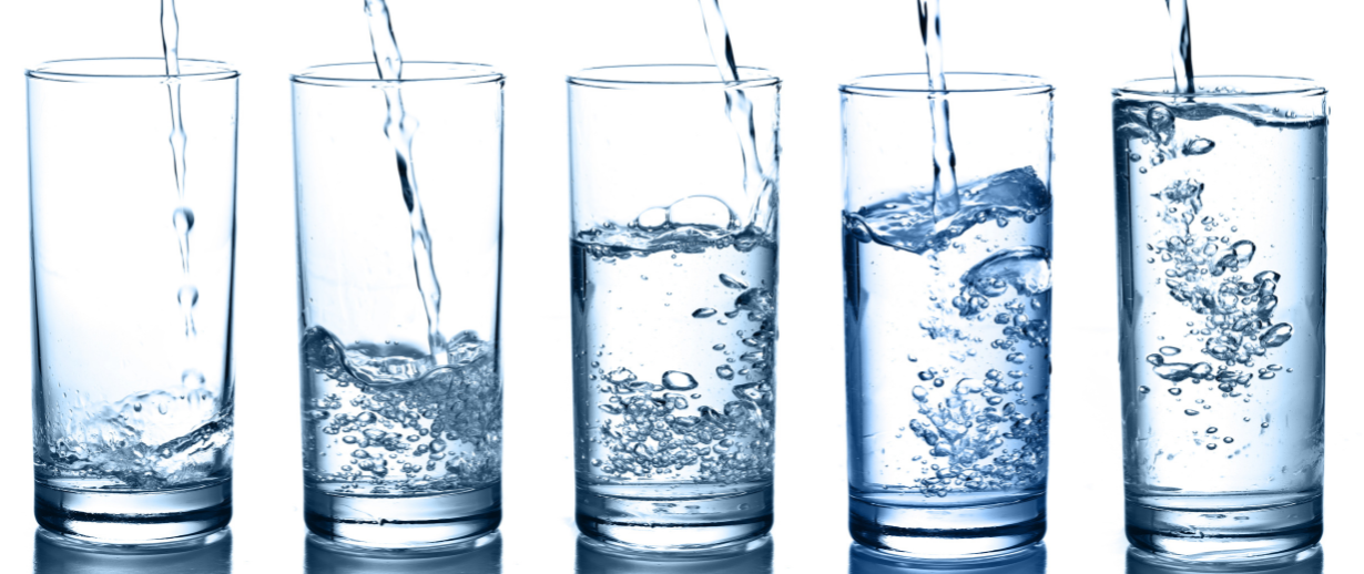 Water being poured into a row of glasses on a white background