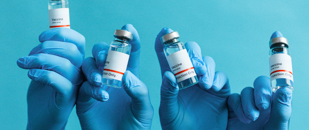 Blue nitrile gloved hands holding vaccination containers