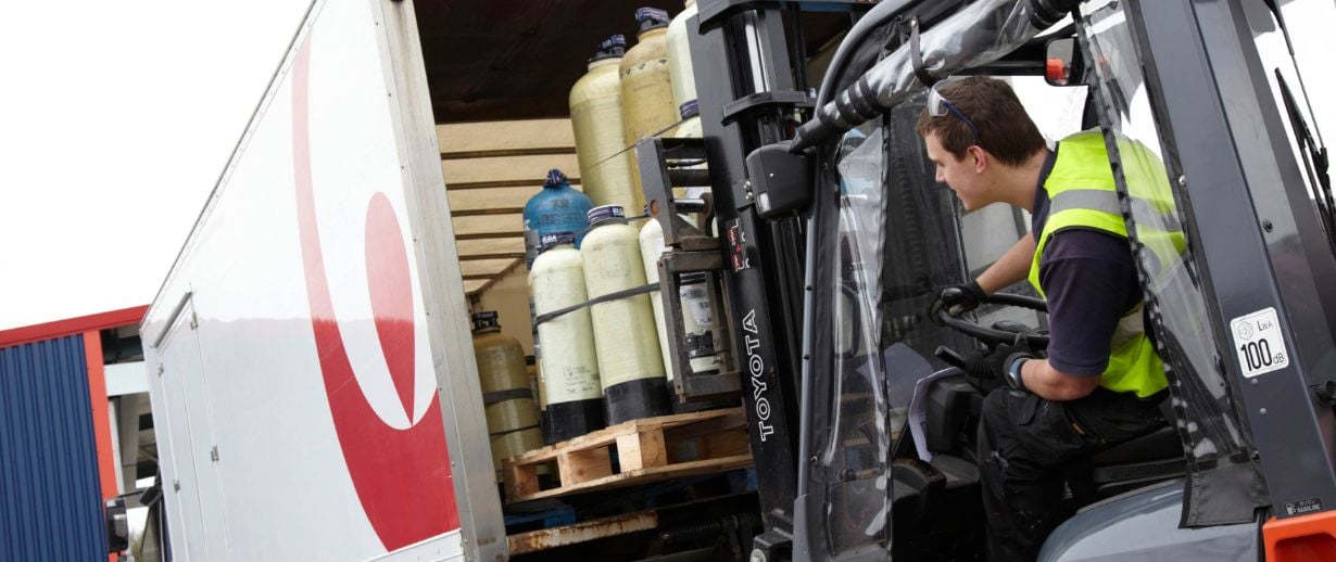 A man using a forklift to lower SDI cylinders from a Veolia branded lorry.