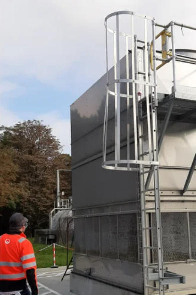 An engineer looking up at a modern cooling tower