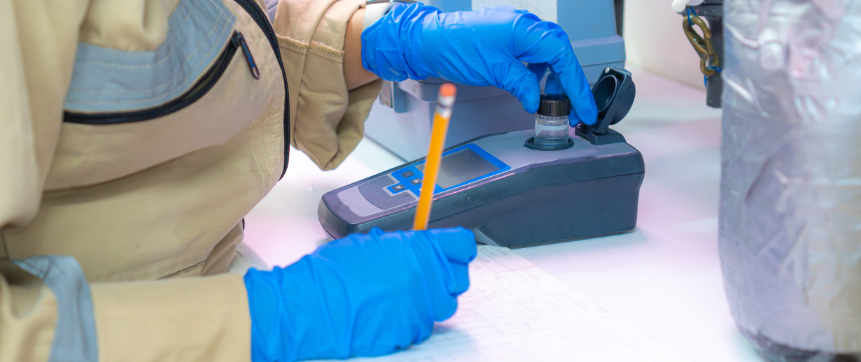 A person wearing PPE checking a water's turbidity level. 